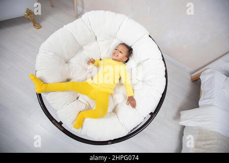 Fotografiert von oben ein kleines afrikanisches Mädchen in einem Sessel. Stockfoto