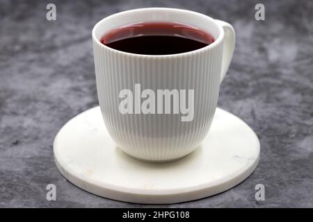 Apfeltee (Hibiscus-Tee) auf dunklem Hintergrund. Medizinischer asiatischer Kräutertee. Früchtetee mit Hibiskus, Hagebutte, Orangenschale, Zitronenschale und Apfel F Stockfoto