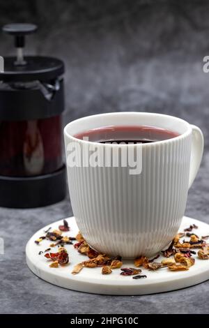 Apfeltee (Hibiscus-Tee) auf dunklem Hintergrund. Medizinischer asiatischer Kräutertee. Früchtetee mit Hibiskus, Hagebutte, Orangenschale, Zitronenschale und Apfel F Stockfoto