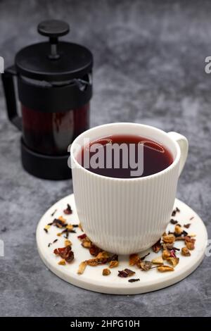 Apfeltee (Hibiscus-Tee) auf dunklem Hintergrund. Medizinischer asiatischer Kräutertee. Früchtetee mit Hibiskus, Hagebutte, Orangenschale, Zitronenschale und Apfel F Stockfoto