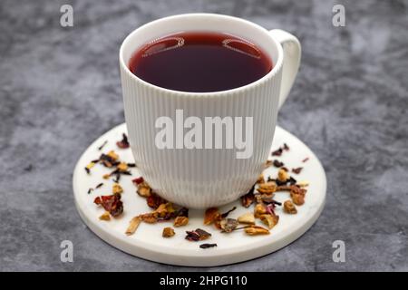 Apfeltee (Hibiscus-Tee) auf dunklem Hintergrund. Medizinischer asiatischer Kräutertee. Früchtetee mit Hibiskus, Hagebutte, Orangenschale, Zitronenschale und Apfel F Stockfoto