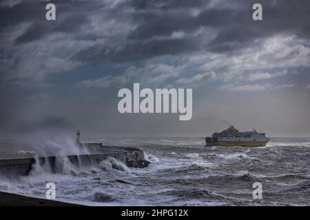 Newhaven Lighthouse, Großbritannien, 21st. Februar 2022. Eine Fähre, die den Hafen verlässt und am Leuchtturm von Newhaven vorbeifährt, während die Wellen auf die Meeresmauer treffen, während Sturm Franklin fegt, dachte an Teile der Südküste Englands. Quelle: Steven Paston/Alamy Live News Stockfoto