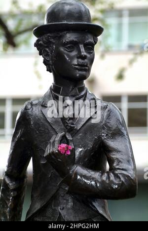 Bronzestatu an Charlie Chaplin mit frischen Blumen. London, Großbritannien. Stockfoto