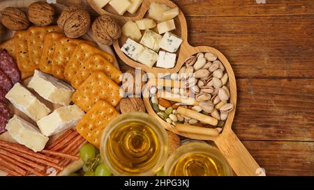 Snacks für Wein. Käse- und Fleischplatte. Wurst, Käse, Nüsse, Trauben, Cracker auf Holzgrund Stockfoto