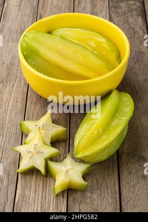 Starfruits mit Scheiben in einer Schüssel über einem Holztisch. Stockfoto