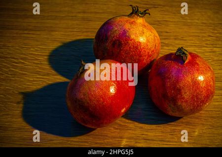 Drei reife Granatäpfel auf dem Holztisch. Stockfoto