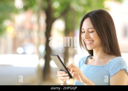 Glückliche asiatische Frau mit Smartphone lächelnd zu Fuß in der Straße Stockfoto