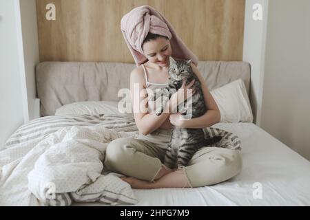 Lächelnde Frau hält und spielt mit einer niedlichen lustigen Katze zu Hause Stockfoto