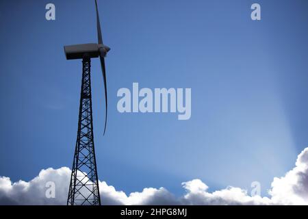 Eine moderne Windturbine vor einem blauen und teilweise bewölkten Himmel Stockfoto