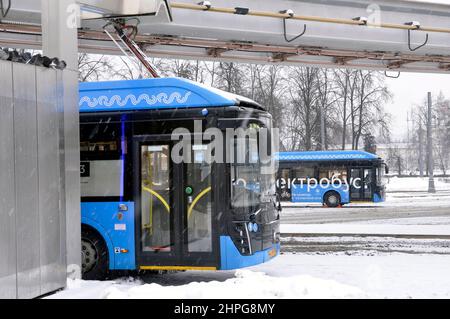 Elektrobus an der Ladestation während des Ladevorgangs. Arbeiten Sie unter harten Winterbedingungen. Schlechte Aufnahmebedingungen – es schneit. Stockfoto
