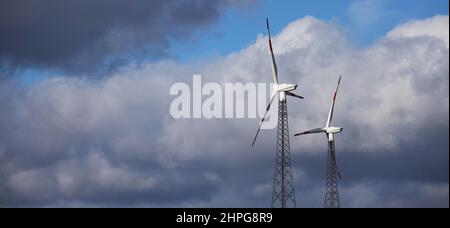 Moderne Windturbinen vor stürmischem Himmelspanorama Stockfoto