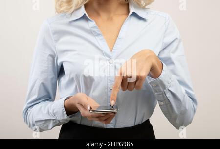 Moderne Technologien in unserem Leben. Geschäftsfrau mit modernem Smartphone, zeigt mit dem Finger auf den Bildschirm Stockfoto