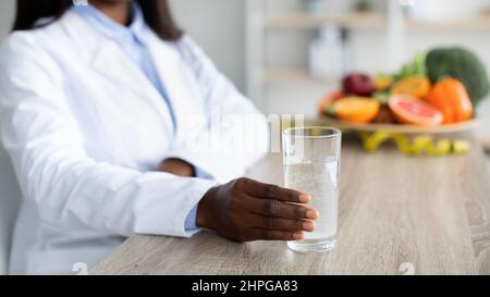 Entgiftung und Reinigungskonzept. Ernährungsberaterin hält ein Glas Wasser und empfiehlt, täglich Wasser zu trinken Stockfoto