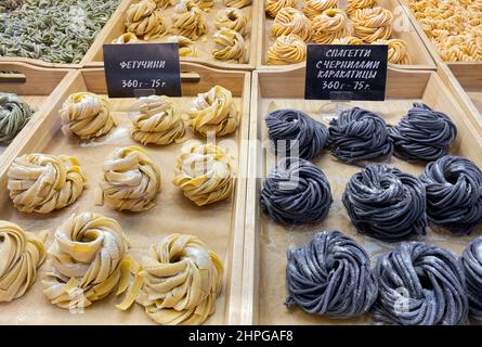 Auf dem Food Court wird nach Gewicht eine Vielzahl von handgefertigten Spaghetti verkauft. Auf Russisch sind verschiedene Nudelsorten geschrieben: Fettuccine, Nudeln mit Tintenfischfarbe, und Stockfoto