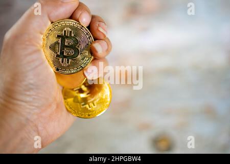 Nahaufnahme einer goldenen Münze mit dem Bitcoin-Symbol in der Hand. Junge Hand hält Kryptowährung Münze, Geld Münzen digital, BTC. Stockfoto