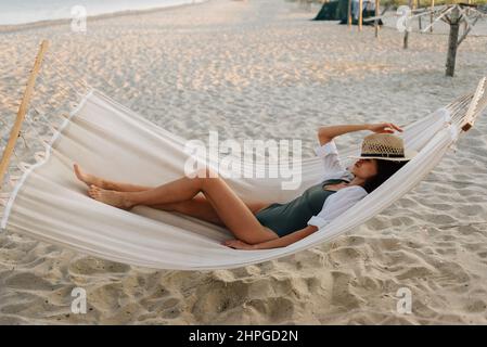 Urlaub Thailand. Eine junge europäische Frau ruht in einer Hängematte an einem leeren Strand. Platz kopieren. Stockfoto