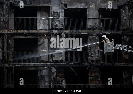 Essen, Deutschland. 21st. Februar 2022. Ein Feuerwehrmann löscht von einer Leiter aus. Im westlichen Viertel der Stadt war seit dem frühen Montagmorgen ein ganzer Wohnblock in Flammen aufgegangen. Das Feuer war kurz nach Mitternacht in der Bargmannstraße ausgebrochen. Die Flammen breiten sich schnell über mehrere Stockwerke aus. Es ist noch unklar, ob Menschen verletzt wurden. Quelle: Fabian Strauch/dpa/Alamy Live News Stockfoto