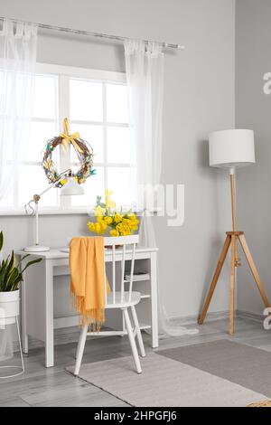 Arbeitsplatz mit schönen Tulpen und Osterkranz im hellen Raum Stockfoto