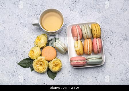 Komposition mit leckeren Makronen, einer Tasse Tee und Blumen auf hellem Hintergrund. Feier zum Internationalen Frauentag Stockfoto