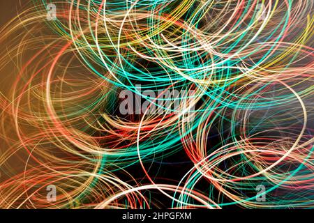 Abstrakte geschwungene Linien, die kunstvoll mit farbigen weihnachtslichtern gestaltet wurden. Leichte Lackierung Stockfoto
