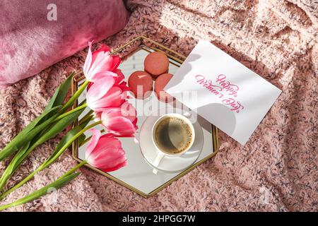 Tablett mit leckerem Frühstück, Grußkarte und Tulpenblumen für die Feier zum Internationalen Frauentag auf dem Bett Stockfoto