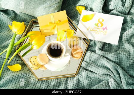 Tablett mit leckerem Frühstück, Geschenk, Grußkarte und Tulpenblumen für die Feier zum Internationalen Frauentag auf dem Bett Stockfoto