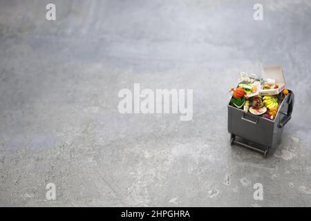 Mülltonne, Bild von Lebensmittelabfällen in Miniatur. Die Briefe der Pizzabox sind fiktiv. Stockfoto