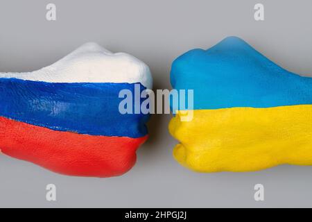 Flaggen der Ukraine und Russlands Flagge auf Händen schlagen sich gegenseitig auf hellgrauem Hintergrund der Weltkarte, Ukraine vs. Russland im Krisenkonzept des Weltkriegs Stockfoto