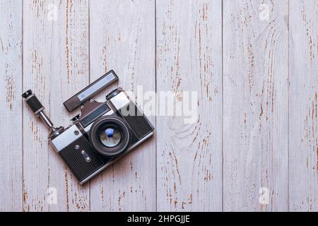 Eine alte Retro-Kamera mit Selbstauslöser und Entfernungsmesser liegt auf dem Tisch. Holzhintergrund Stockfoto