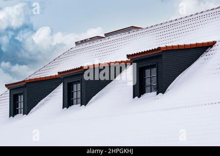 Reihe von Dachgauben auf einem Dach unter einer Schicht von Neuschnee Stockfoto