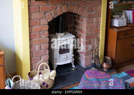 Ein freistehender offener Kamin mit Holzofen im traditionellen Stil in einem gemauerten Kamin in einer heimischen Lounge. England Stockfoto