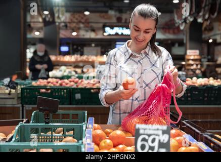 Eine junge Frau wählt Früchte in einem Supermarkt. Stockfoto