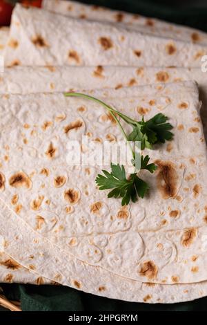 Lavasch rollte auf einem hölzernen Hintergrund, dünnes traditionelles orientalisches Brot, armenisches Fladenbrot-Makro, Nahaufnahme Stockfoto