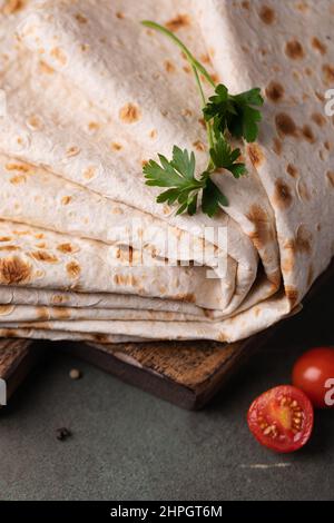 Lavasch rollte auf einem hölzernen Hintergrund, dünnes traditionelles orientalisches Brot, armenisches Fladenbrot-Makro, Nahaufnahme Stockfoto