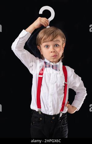 Entzückende kleine Vorschuljunge schön gekleidet hält Frage Zeichen. Stockfoto