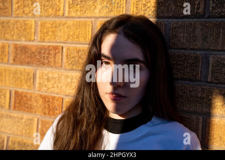 Junge Frau in Retro-Kleidung, die vor einer Ziegelwand steht Stockfoto