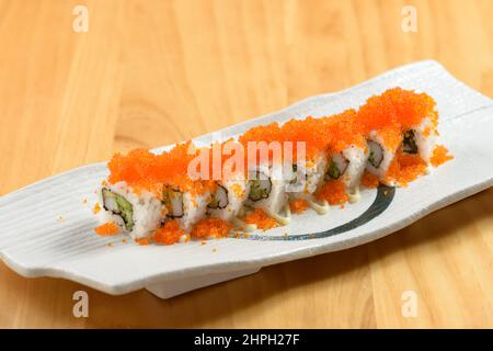 Japanisches Sushi Essen Regenbogen Maki in einem weißen Tablett isoliert auf Holztisch Draufsicht Stockfoto
