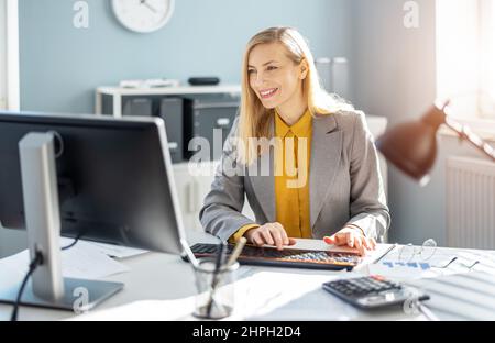Lächelnde Frau, die im Büro arbeitet Stockfoto