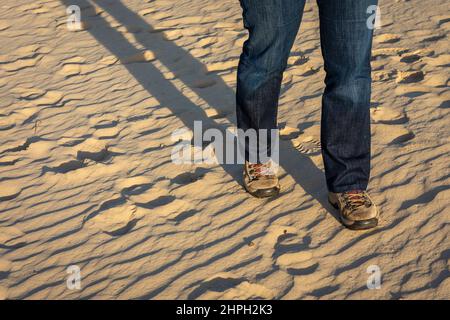 Wandern im Sand, Füße mit Wanderschuhen in den beleuchteten Sanddünen Stockfoto