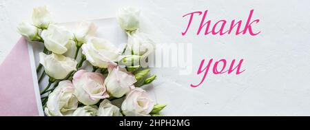 Ein floraler Touch macht diese Note zu einem eleganten Dankeschön an eine Hochzeit oder Einladung mit einem Bouquet von sanften weißen Blüten von Lisianthus im Umschlag. Web Stockfoto