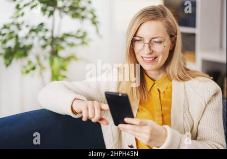 Frau mit Smartphone zu Hause Stockfoto