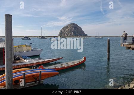 Morro Rock, ein uralter vulkanischer Plug, ist entlang der kalifornischen Central Coast zu sehen, während Boote des Morro Bay Hafens im Vordergrund stehen Stockfoto