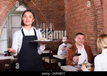 Positive weibliche Kellner die Gäste zu Land Restaurant und lächelnd Stockfoto