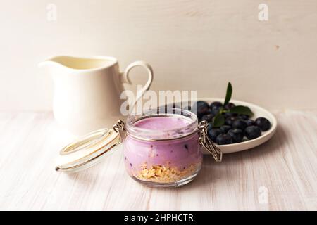 Haferflocken Müsli oder Müsli mit Joghurt-Smoothie, frischer Heidelbeere und Keramikkännchen Milch Stockfoto