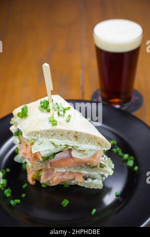 Köstliches Lachs-Sandwich aus der Nähe und ein Glas Bier. Stockfoto