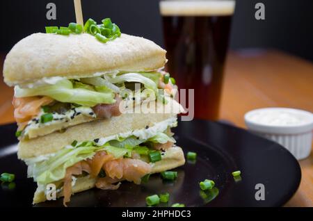 Köstliches Lachs-Sandwich aus der Nähe und ein Glas Bier. Stockfoto