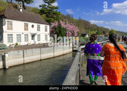 Zwei Frauen mit Saris machen einen Spaziergang entlang der Holzbrücke zur Marsh Lock an der Themse in Henley-on-Thames, Oxfordshire, England, Großbritannien Stockfoto