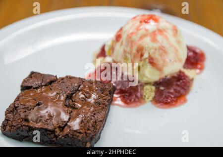 Nahaufnahme eines köstlichen Brownie-Nachtischs mit Speiseeis und Himbeer-Bier Stockfoto