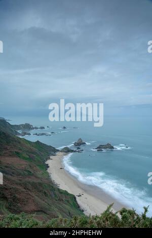 Wilde Klippen und weitläufiger Strand in Loiba an der Nordküste Galiciens, gefangen mit weichem Licht und Atlantiknebel in einer dramatischen Küstenlandschaft. Stockfoto