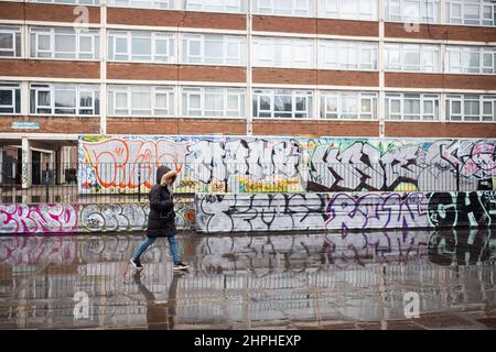 Eine einsame Frau geht an einer Graffiti-Wand in der Old Street, East London, Großbritannien, vorbei Stockfoto